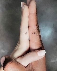 two hands holding each other with the word love tattooed on their fingers