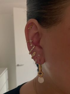 a woman wearing gold ear cuffs and earrings