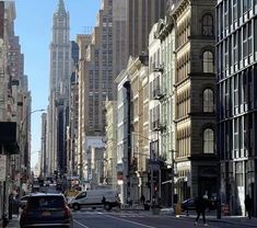 a city street filled with lots of tall buildings and cars driving down the middle of it