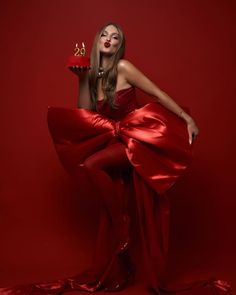 a woman in a red dress is holding a candle and wearing a pair of scissors