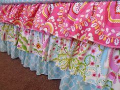 the bed skirt is lined with pink and blue fabric, which has floral designs on it