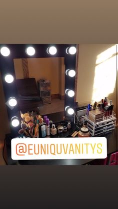 the vanity mirror has lights on it and is next to a table with makeup products