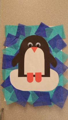 a paper cut out of a penguin sitting on top of a blue piece of paper