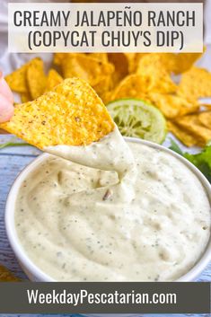 a hand dipping a tortilla chip into a bowl of creamy jalapeno ranch copycat chuys dip