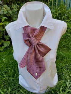 a white shirt with a pink tie on it sitting in front of some grass and trees