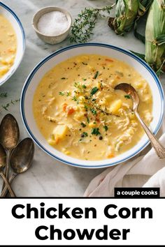 two bowls of chicken corn chowder on a table with spoons and garnish