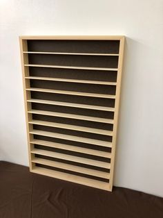 a book shelf sitting on top of a bed next to a white wall and brown sheets