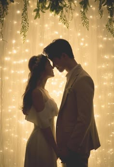 a man and woman standing next to each other in front of a curtain covered with lights