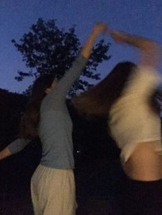 two women are dancing outside at night