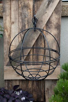 a metal ball hanging from the side of a wooden wall with purple flowers in it