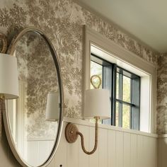 a bathroom with a mirror, sink and lamp on the wall next to it in front of a window