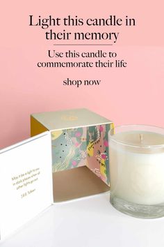 a white candle sitting next to a pink box