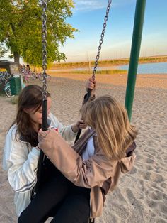 two women sitting on swings at the beach