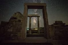 the milky is shining brightly in the sky above an ancient structure with columns and pillars