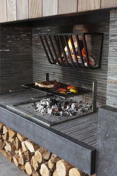 an outdoor grill with logs and food cooking on it