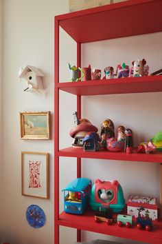 a red book shelf filled with lots of toys