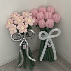 two vases with flowers in them sitting next to each other on the floor near a wall