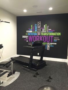 a room with a treadmill, exercise equipment and a wall that has words written all over it