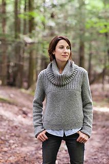 a woman standing in the woods wearing a cowl neck sweater