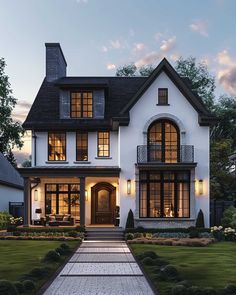 a large white house with lots of windows and lights on the front door is lit up at night