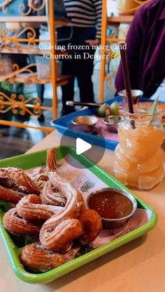 there is a green tray with food on it and people standing in the background behind it