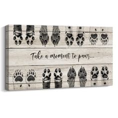 a wooden sign that says take a moment to paw with an image of many paws on it