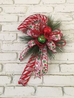 a red and green christmas bow with candy canes hanging on a white brick wall