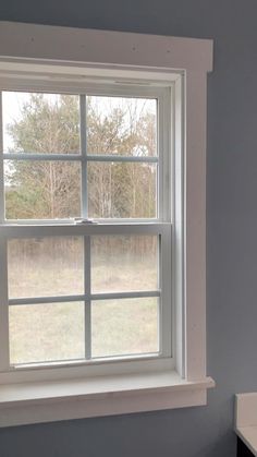 an empty bathroom with a toilet and window in it's corner, looking out onto the field