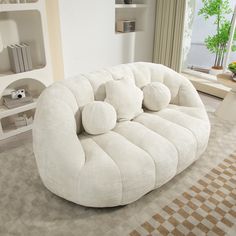 a large white couch sitting on top of a living room floor next to a window