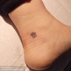 a small tattoo on the ankle of a woman's foot with an animal paw