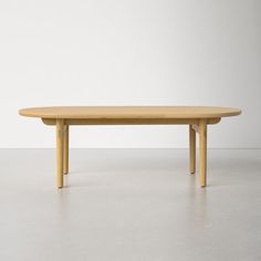 an oval wooden table sitting on top of a white floor