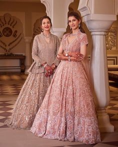 two women standing next to each other in formal wear, one wearing a pink gown