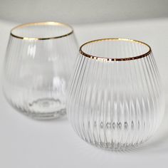 two clear glass vases sitting on top of a white table next to each other