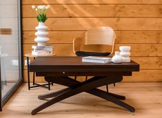 a chair and table with vases on it in front of a wood paneled wall