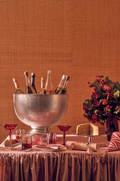 a table topped with lots of bottles of wine next to a vase filled with flowers