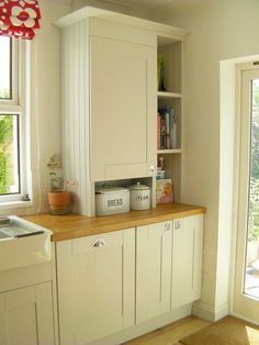 an image of a kitchen with white cabinets and wood counter tops on the bottom shelf