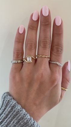 a woman's hand with three different rings on her fingers and one is wearing a sweater