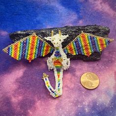 a small beaded bat sitting on top of a purple surface next to a coin