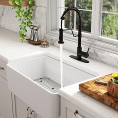 a kitchen sink sitting under a window next to a cutting board with fruit on it