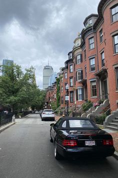 cars are parked on the street in front of row houses and apartment buildings under cloudy skies