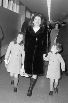 an old black and white photo of two women walking with children in the subway station