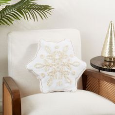 a white chair with a decorative pillow on it next to a potted palm tree