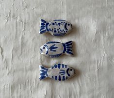 three blue and white ceramic fish sitting on top of a tablecloth covered floor next to each other