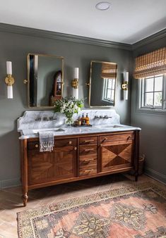 a bathroom with two sinks, mirrors and rugs on the floor in front of it