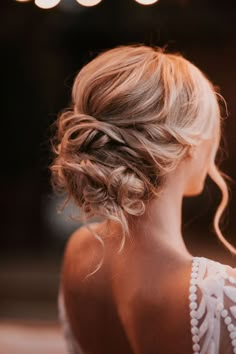 a woman with blonde hair wearing a white dress and pearls in her hair is looking off to the side