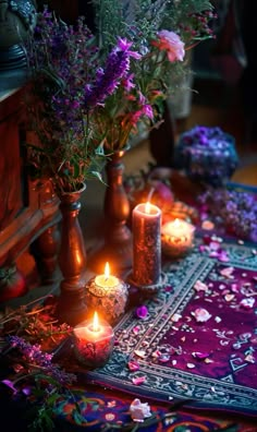 candles are lit on a table with purple flowers in vases and other decorative items