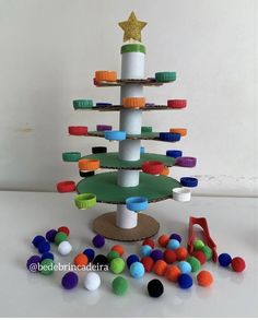 a christmas tree made out of toilet paper rolls and plastic cups is surrounded by colorful balls