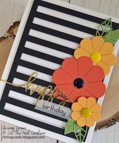 a happy birthday card with flowers and leaves on the front, sitting on top of a piece of wood