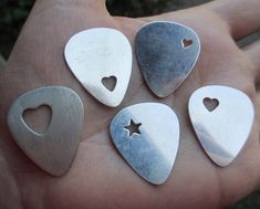 four different sized heart shaped pendants on a person's hand with one star in the middle