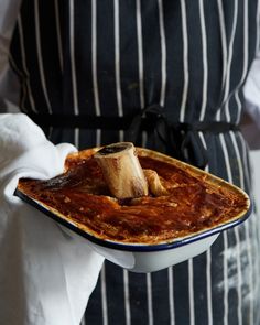 a person in an apron holding a plate with food on it